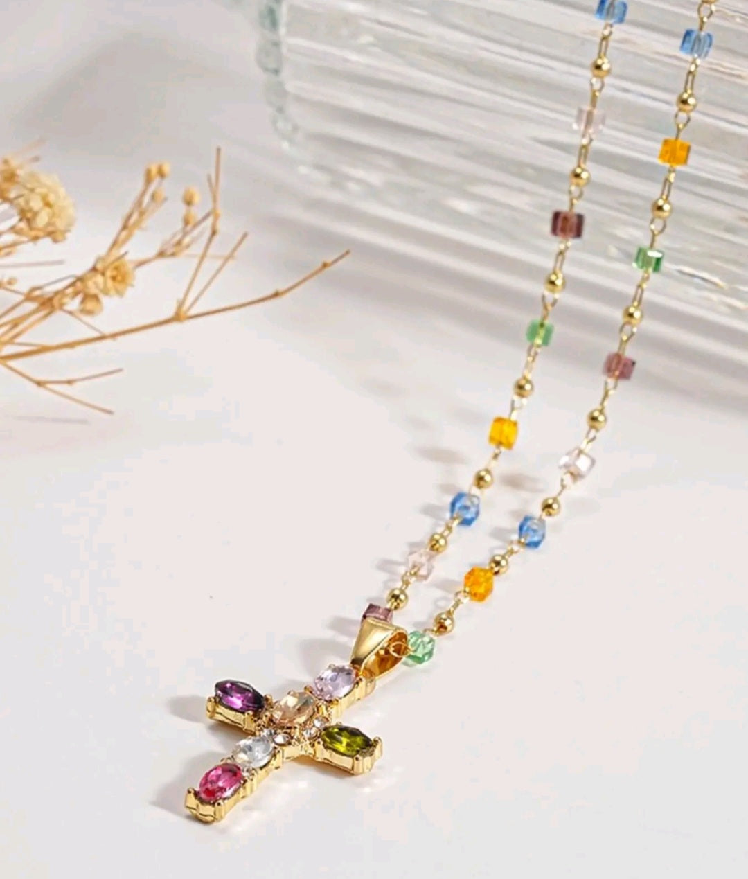 Collar con dije de cruz de piedras preciosas multicolores, un accesorio de estilo religioso y moderno que resalta por su diseño vibrante.