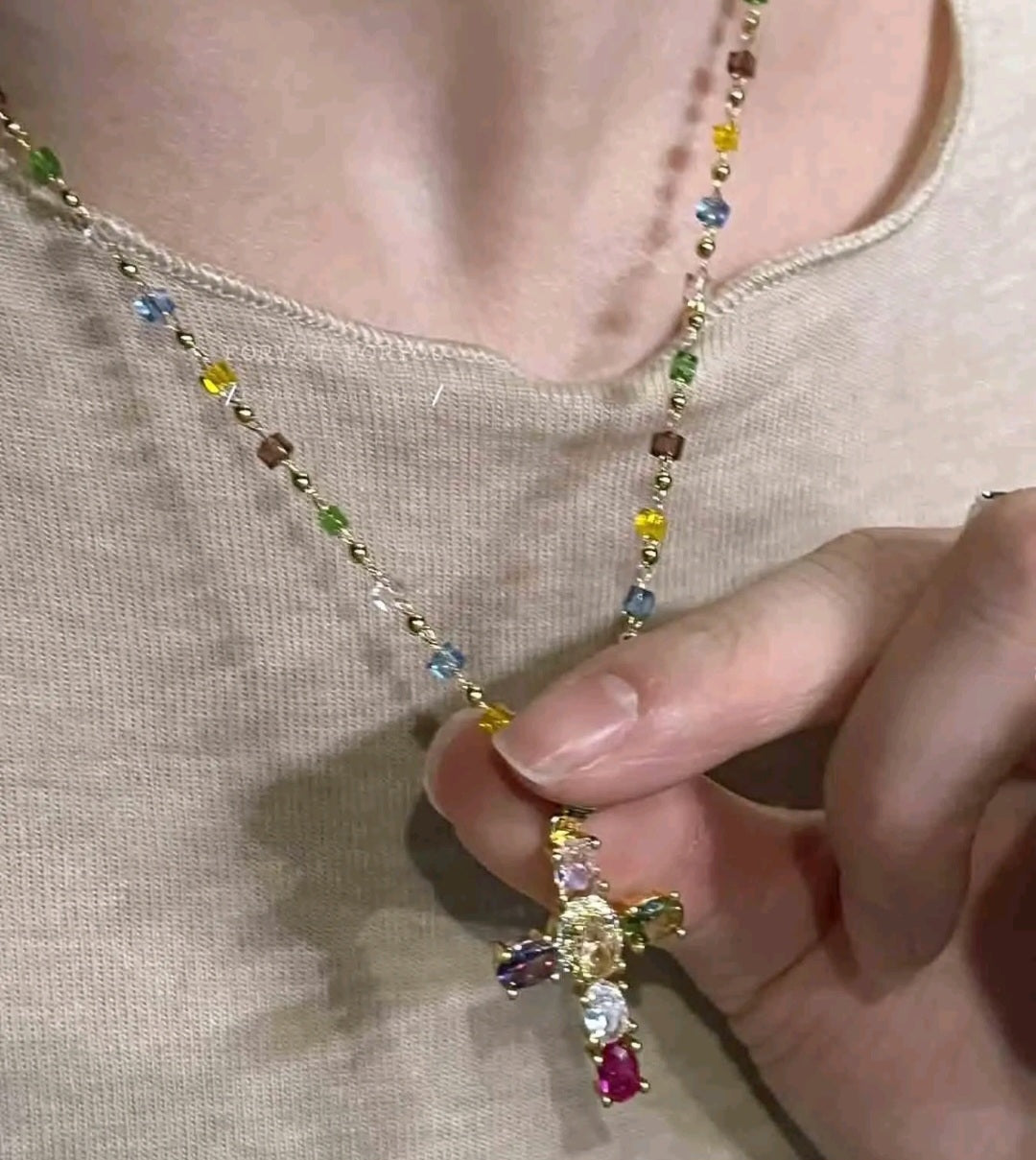 Collar con dije de cruz de piedras preciosas multicolores, un accesorio de estilo religioso y moderno que resalta por su diseño vibrante.