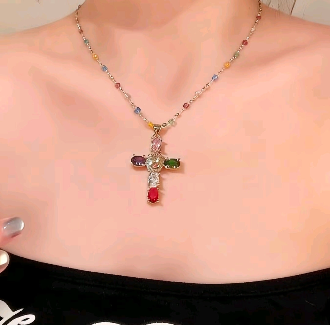 Collar con dije de cruz de piedras preciosas multicolores, un accesorio de estilo religioso y moderno que resalta por su diseño vibrante.