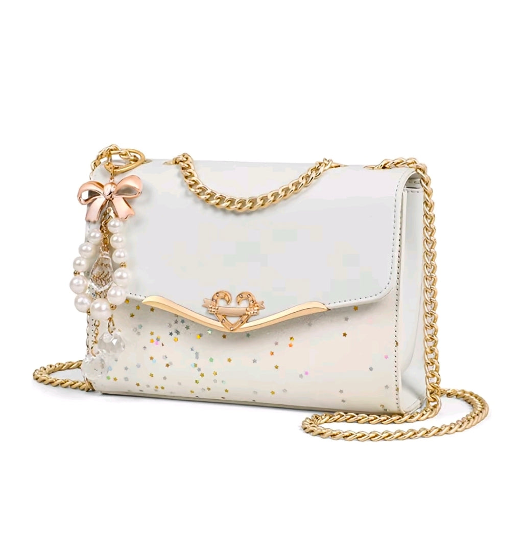 Esta cartera bandolera de diseño estructurado destaca por su estética femenina y sus detalles de fantasía con acabados metálicos en tono dorado.